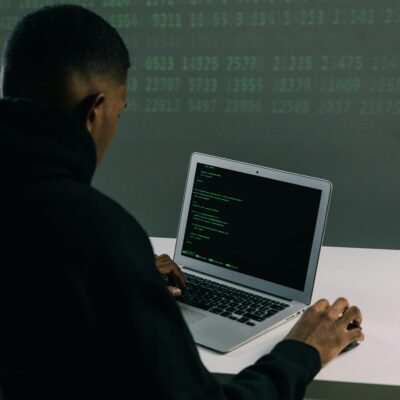 A programmer engaged in coding on a laptop in a tech-focused workspace with a digital interface.